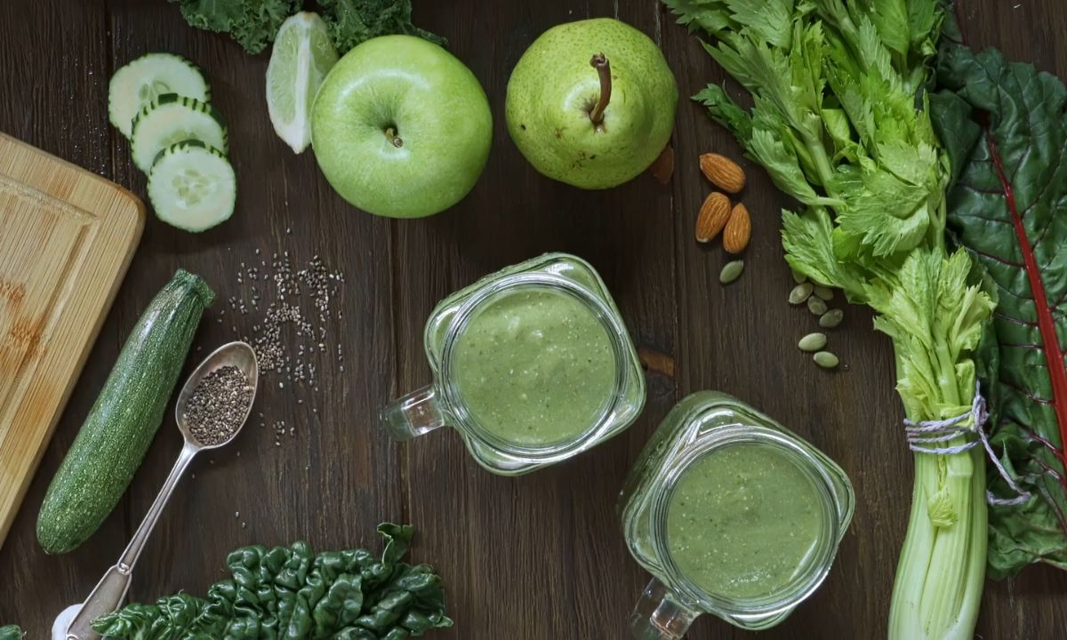 prikaz zelenog detoks sokića u teglicama i oko njih krastavci, jabuke, čija seme, celer