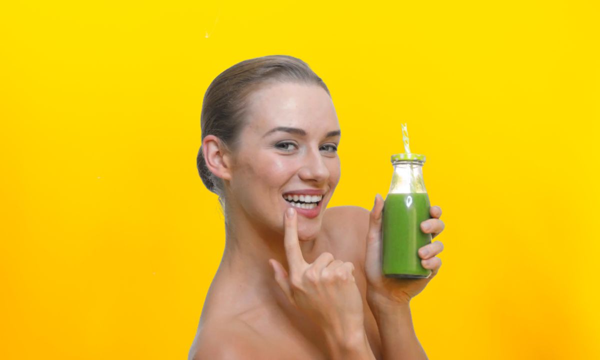 devojka pije detoks sok, žuta pozadina iza nje