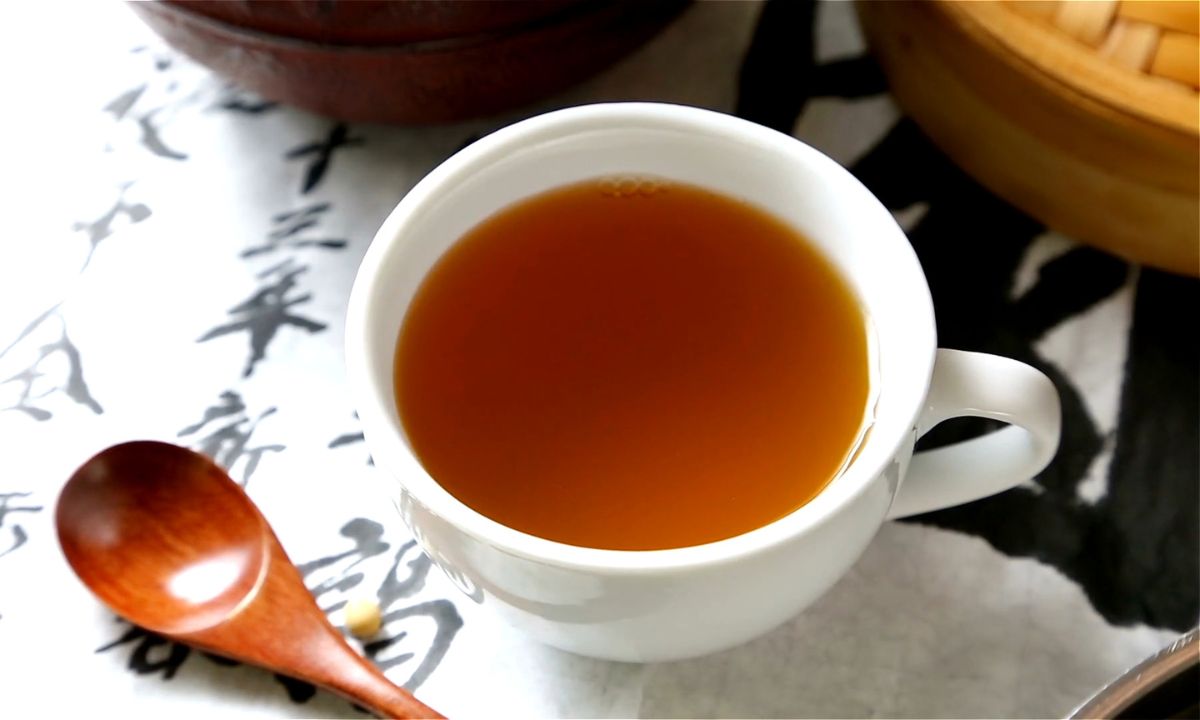 prikaz zelenog čaja u beloj šoljici na stolu na kom je drvena kašičica